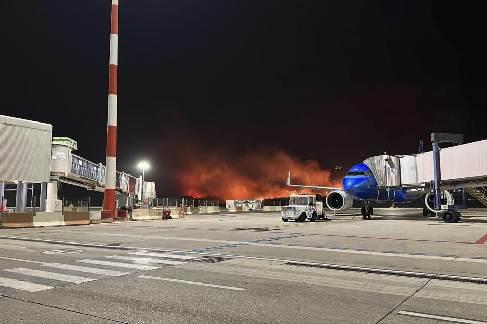 This photo provided by Palermo Airport Press Office shows plumes of fire and smoke covering the hills surrounding Palermo's airport, Sicily, Italy, late Monday night, July 24, 2023, causing its shutdown and leaving planes trapped on the tarmac. The airport reopened at 11am (9gmt) Tuesday 25 only for departing planes, after twentyfour flights were cancelled overnight and four were sent to the nearby airport in Trapani. (Palermo Airport Press Office via AP)