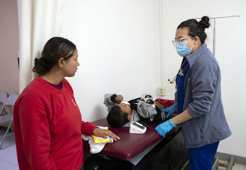 Dr. Krystal Lopez, right, with the Texas Tech University Health Sciences Center in El Paso, Texas, provides medical attention to Honduran migrant Elvin Cruz, 5, as his mother Diana Rosales looks on at a government-run shelter in Ciudad Juarez, Mexico, on Sunday, Dec. 18, 2022. (AP Photo/Andres Leighton)