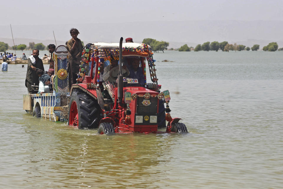 Displaced people who fled from flood-hit areas sit on a tractor to cross a flooded area at Sehwan, in Pakistan's southern Sindh province, August 31, 2022. / Credit: AKRAM SHAHID/AFP/Getty