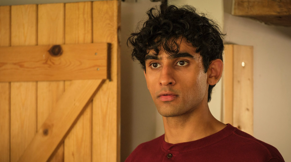 A young man is stood in a house, looking slightly away from the camera