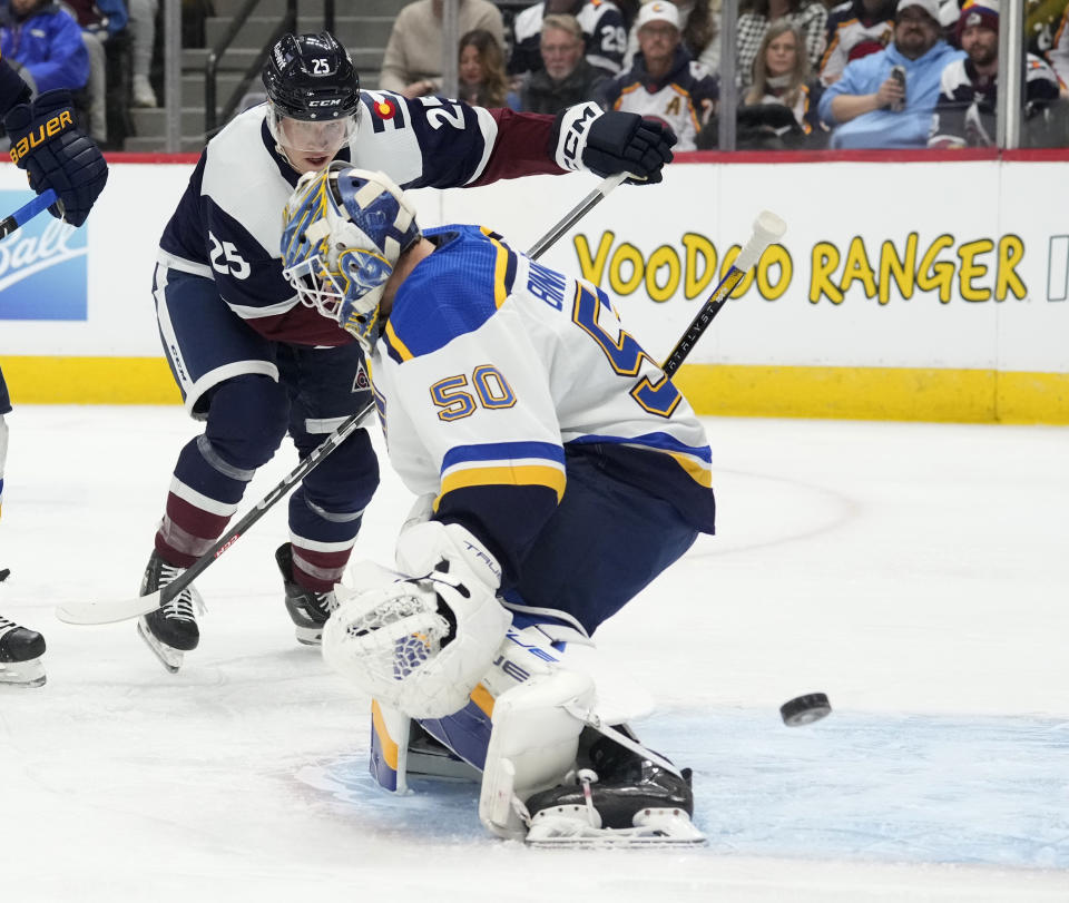 St. Louis Blues goaltender Jordan Binnington, front, deflects a shot from Colorado Avalanche right wing Logan O'Connor during the first period of an NHL hockey game Saturday, Nov. 11, 2023, in Denver. (AP Photo/David Zalubowski)