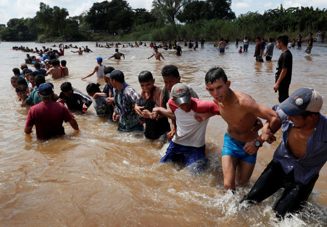 Migrants formed a human chain to pull people across a river between Guatemala and Mexico before continuing their trek toward the United States. (Photo: Leah Millis/Reuters)