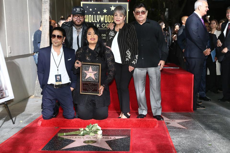 chris perez, ab quintanilla iii, suzette quintanilla, marcella samora, and abraham quintanilla jr pose for a photo as they kneel and stand behind a star bearing selena quintanillas name