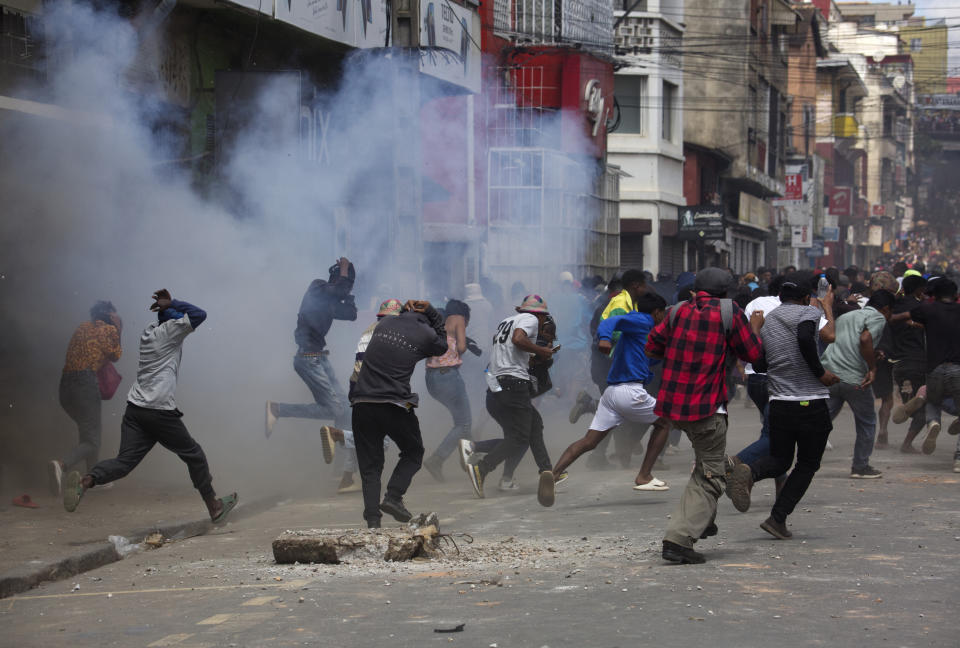Anti-election protesters flee teargas fired by police in Antananarivo, Saturday Nov. 11, 2023. Madagascar's Andry Rajoelina is pushing ahead with a presidential election, Thursday, Nov. 16 that could give him a third term, even as opposition protests roil the country and the majority of candidates have announced a boycott. (AP Photo/Alexander Joe)