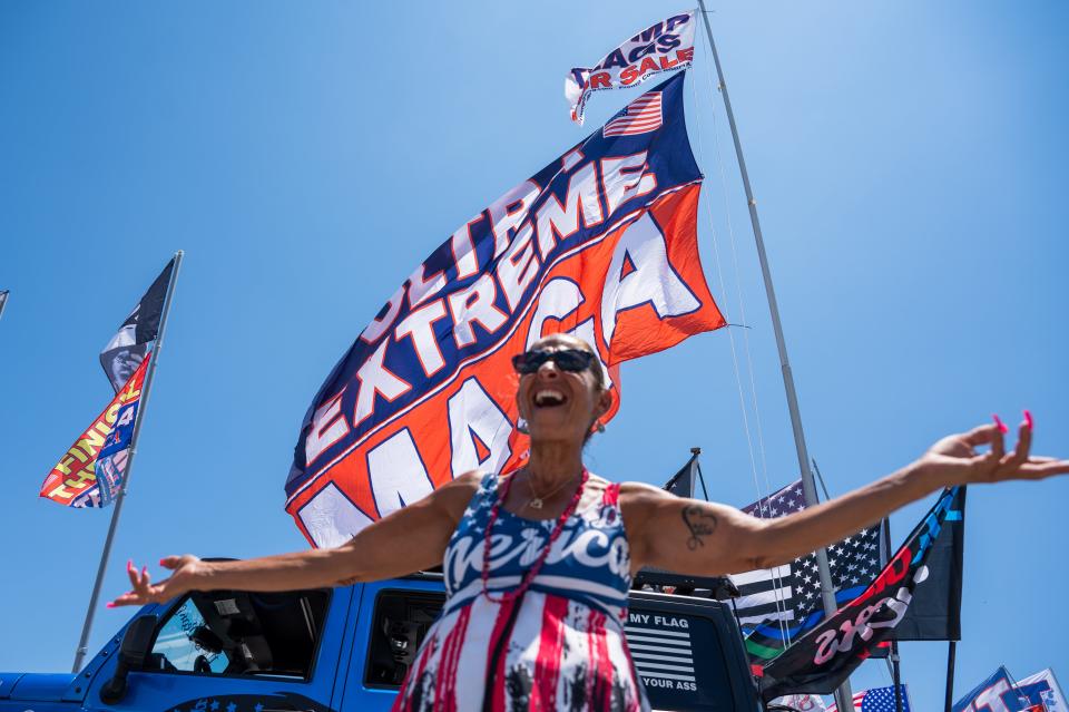 Debbie Macchia, Boynton Beach, poses for a picture while standing under a flag that reads 