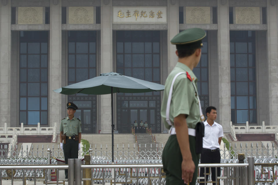 In this Monday, July 9, 2012 photo, a Chinese paramilitary policeman, front, a soldier in plain clothes, center right, and uniformed soldiers guard in front of an entrance to a mausoleum in the center of the Tiananmen Square that displays Mao Zedong's body in Beijing, China. Tiananmen Square, the world's largest public square, is surrounded by buildings of political and cultural significance and is visited by thousands of tourists daily. (AP Photo/Alexander F. Yuan)