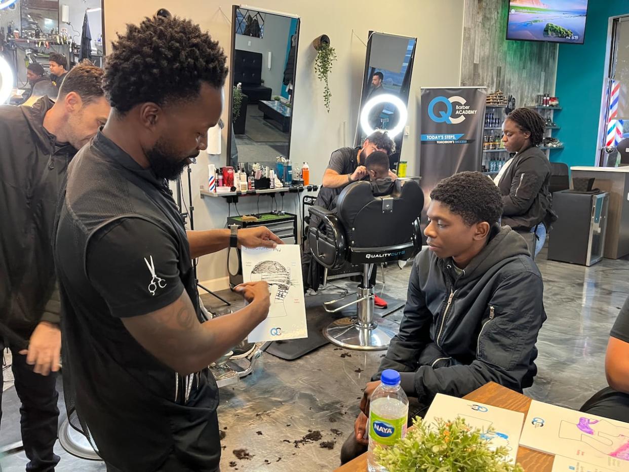 Nasir Abdul Wahab, right, is learning how to cut hair thanks to William Biney, left, who owns Quality Cuts West Island. Biney is teaching students the trade in 10-week program. (Paula Dayan-Perez/CBC - image credit)