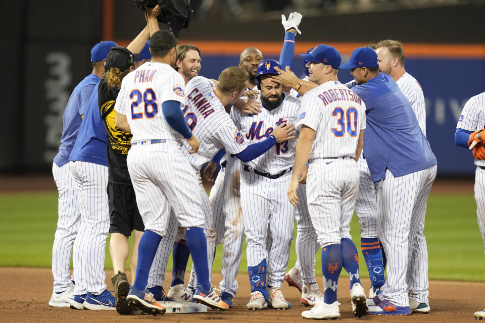 New York Mets' Luis Guillorme, center, celebrates with teammates after hitting a walk-off RBI single during the tenth inning of a baseball game against the Los Angeles Dodgers at Citi Field, Sunday, July 16, 2023, in New York. The Mets defeated the Dodgers in extra innings 2-1. (AP Photo/Seth Wenig)