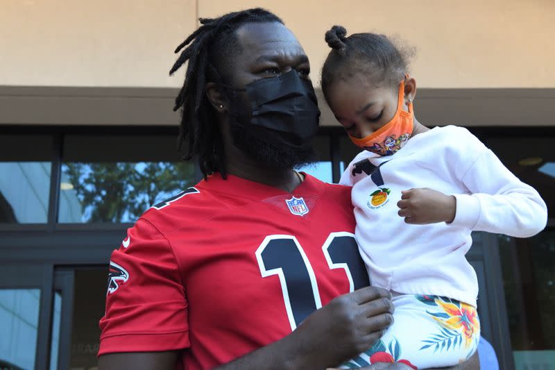 Omar Ceesay, 41, poses with his daughter, Aria Ceesay, 4, as he leaves the Gladys S. Dennard Library after casting his first ballot ever in Atlanta, South Fulton County