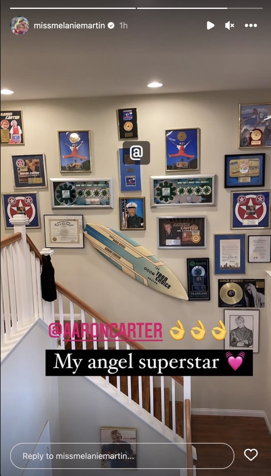 An image of a stairway in a residence hung with Aaron Carter memorabilia, including a surfboard, with a superscription saying: @AARONCARTER, My angel superstar.