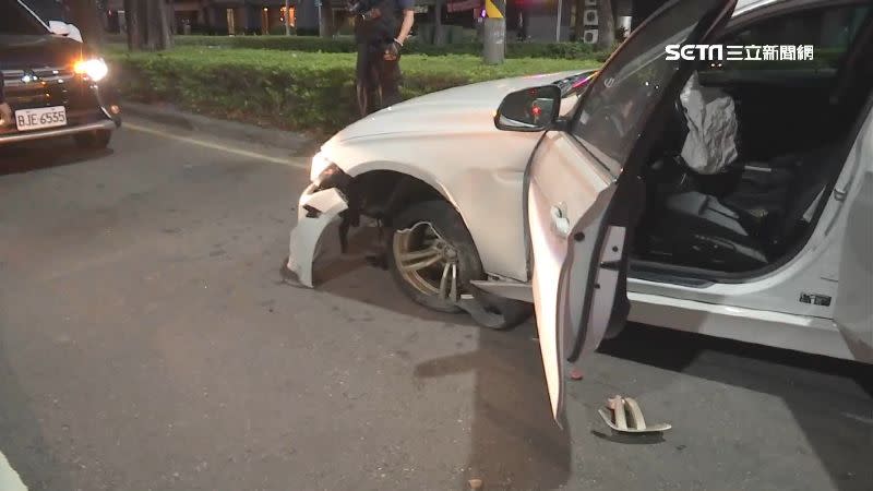 白色名車自撞安全島，保險桿和輪胎嚴重毀損。