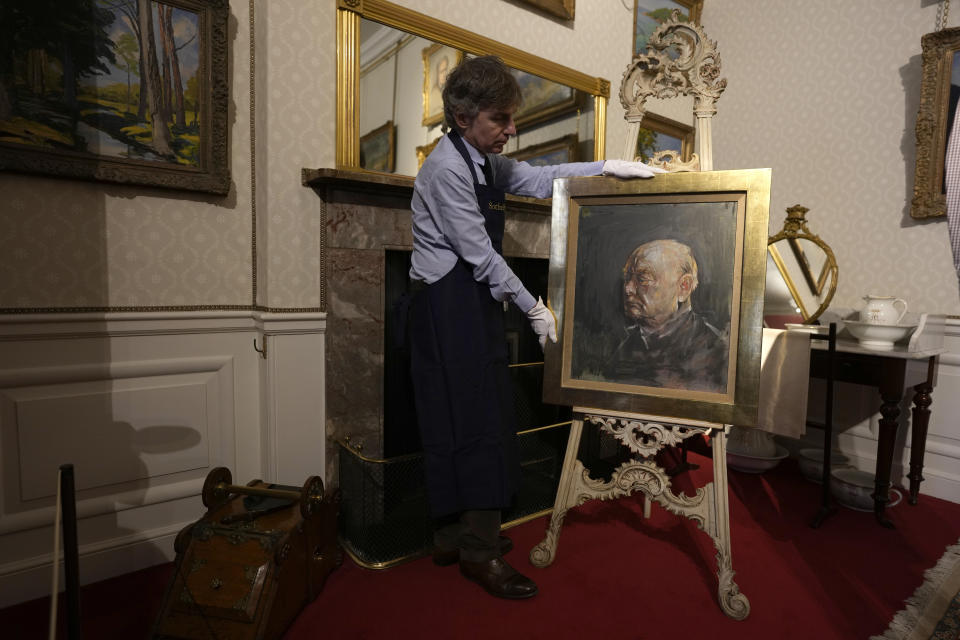 A member of staff from Sotheby's poses for the media with a portrait of the iconic former British Prime Minister Winston Churchill, painted by Graham Sutherland in 1954, at Blenheim Palace, Woodstock, England, Tuesday, April 16, 2024. The portrait will be sold at auction on June 6 with an estimated price of 500-800,000 pounds sterling (US621, 000-1,000,000). Churchill was born at Blenheim Palace on Nov. 30, 1874. (AP Photo/Alastair Grant)