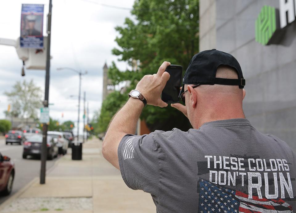 Dave Patron, uncle of U.S. Marine Sgt. Daniel J Patron, who was killed in Afghanistan in 2011, takes a photo of his nephew's banner as it is hung along Lincoln Way in downtown Massillon. The city has put up 15 5-foot banners featuring 29 deceased service members ahead of Memorial Day. Additional banners honoring living veterans and active military members will be added later.