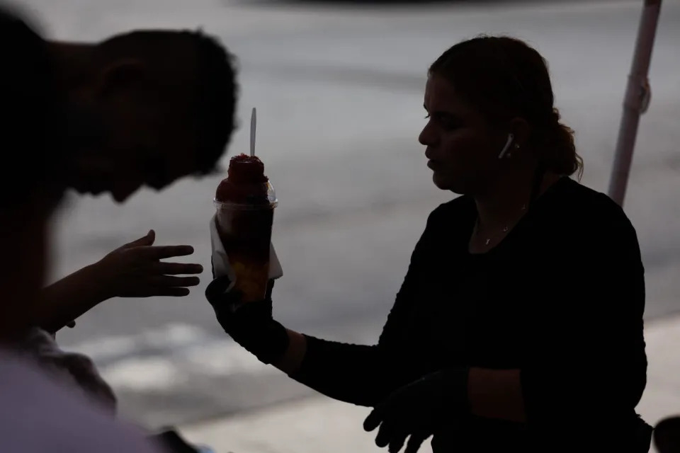 Karina Cerón, de 31 años, sirve un raspado a un cliente durante un día laboral en el que el