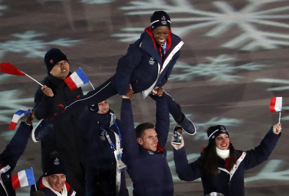 A French athlete is held in the air&nbsp;alongside France's flag.