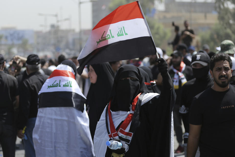 A veiled woman protester holds an Iraqi flag as people gather near the Green Zone area in Baghdad, Iraq, Saturday, July 30, 2022 — days after hundreds breached Baghdad's parliament Wednesday chanting anti-Iran curses in a demonstration against a nominee for prime minister by Iran-backed parties.(AP Photo/Anmar Khalil)