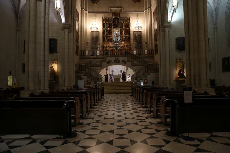 Three people attend a mass at La Almudena Cathedral that is being lived streamed after Catholic masses were suspended during a partial lockdown as part of a 15-day state of emergency to combat the coronavirus disease outbreak, in Madrid