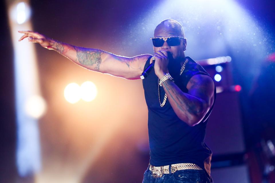 Flo rida signing in stage, with colorful lights on the background.