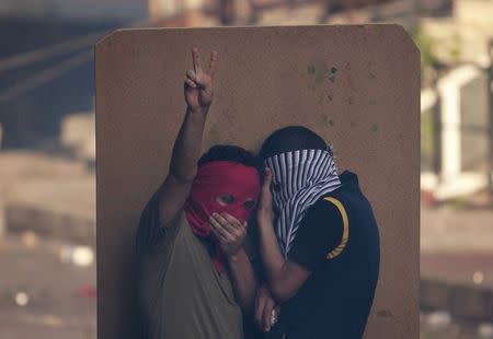 Masked demonstrators take cover behind a shield as they clash with riot police during a funeral ceremony for Gunay Ozarslan, a member of the far-left People's Front who, according to local media reports, was killed by Turkish police during a security operation on Friday, in Istanbul, Turkey July 25, 2015. REUTERS/Kemal Aslan