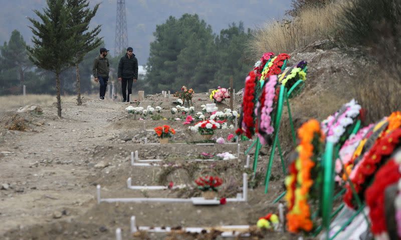 Men walk along graves of soldiers and civilians who were killed during a military conflict over the breakaway region of Nagorno-Karabakh, in Stepanakert