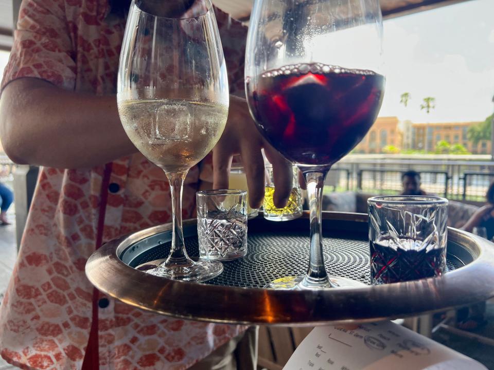 Platter holding two glasses of sangria and two smaller glasses.