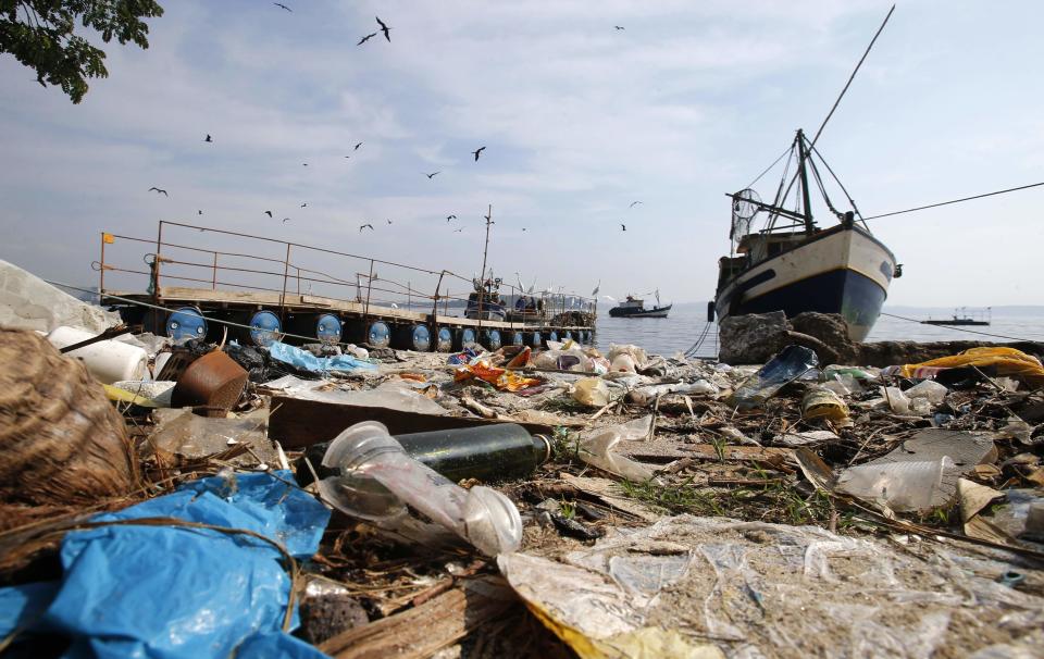 Garbage is seen near a fishing boat on Fundao beach in the Guanabara Bay in Rio de Janeiro March 13, 2014. REUTERS/Sergio Moraes