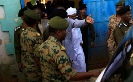 Sudan's ex-president al-Bashir is escorted as he walks out from the National Prison in Khartoum