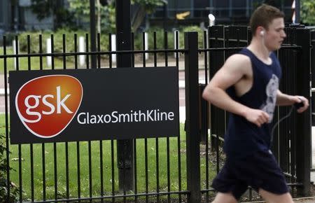 A jogger runs past a signage for pharmaceutical giant GlaxoSmithKline (GSK) in London April 22, 2014. REUTERS/Luke MacGregor