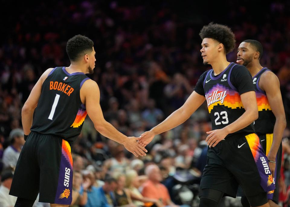 Apr 17, 2022; Phoenix, Arizona, U.S.;  Phoenix Suns guard Devin Booker (1) slaps hands with Phoenix Suns forward Cameron Johnson (23) during Game 1 of the Western Conference playoffs against the New Orleans Pelicans.