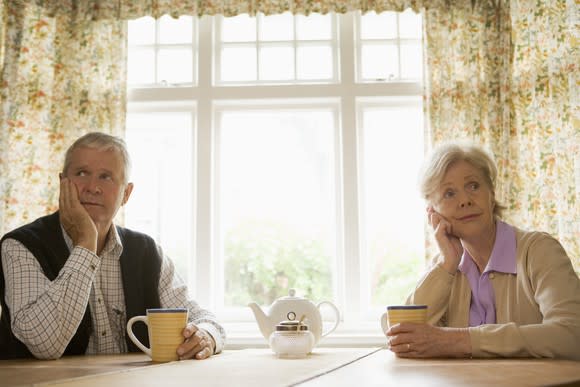 Mature man and woman sitting at a table thinking.