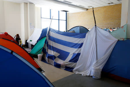 A Greek national flag is used as part of a self-made tent inside the disused Hellenikon airport, where refugees and migrants are temporarily housed, in Athens, Greece, July 13, 2016. REUTERS/Alkis Konstantinidis/File Photo