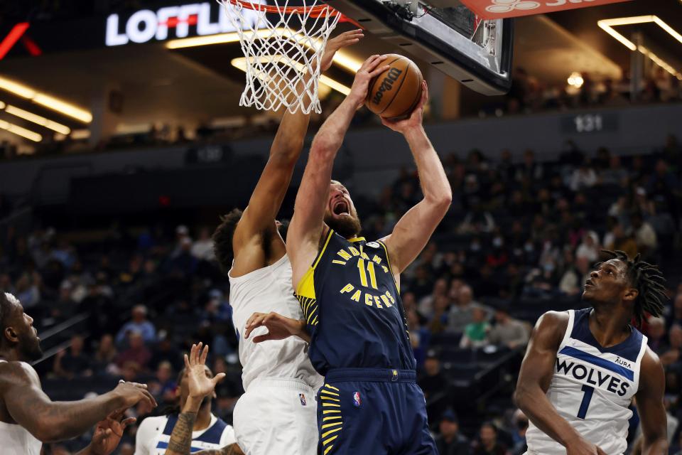 Indiana Pacers forward Domantas Sabonis (11) goes up to the basket against Minnesota Timberwolves center Karl-Anthony Towns (32) during the second half of an NBA basketball game Monday, Nov. 29, 2021, in Minneapolis. Minnesota won 100-98. (AP Photo/Stacy Bengs)