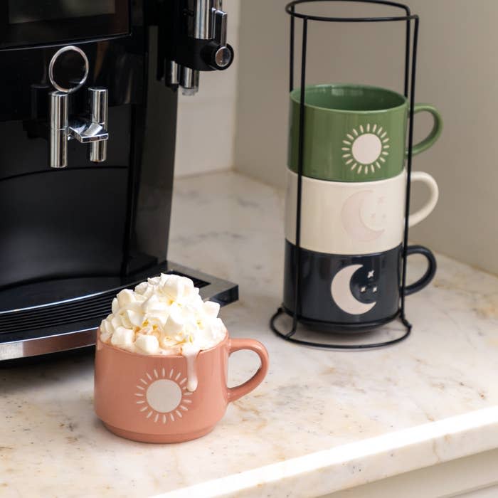 the four different colored mugs with three stacked and one full of whipped cream