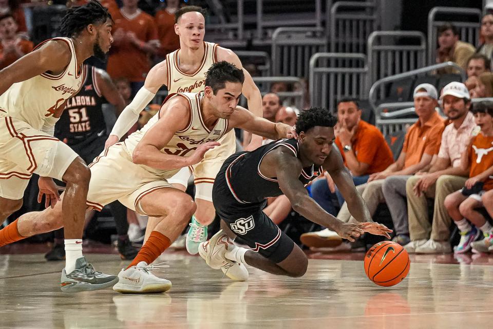 Texas forward Brock Cunningham and Oklahoma State's Eric Dailey Jr. fight for a loose ball during Saturday's 81-65 Longhorns victory.