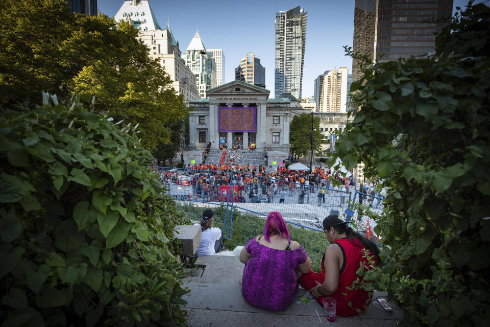 People listen during a ceremony and vigil for the 215 children whose remains were found buried at the former Kamloops Indian Residential School, in Vancouver, British Columbia, on National Indigenous Peoples Day, Monday, June 21, 2021. (Darryl Dyck/The Canadian Press via AP)