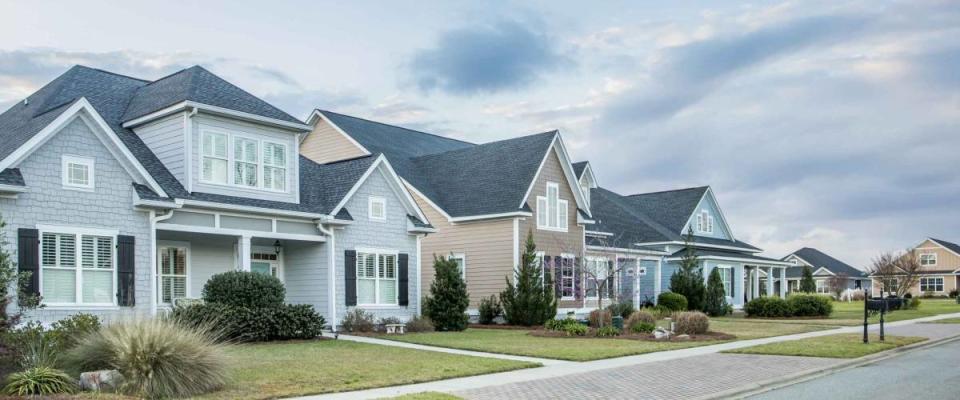 A street view of a new construction neighborhood with larger landscaped homes and houses with yards and sidewalks taken near sunset with copy space