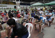 Men who got arrested for violating quarantine health protocols wait for their turn at the Amoranto Sports Complex in metropolitan Manila, Philippines on Wednesday, July 8, 2020. Philippine President Rodrigo Duterte eased one of the world's longest lockdowns in the Philippine capital of more than 13 million people on June 1 after the economy shrank in the first quarter in its first contraction in more than two decades. (AP Photo/Aaron Favila)