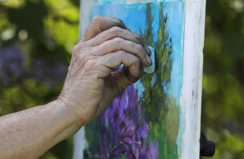 Colette Savage adds highlights of light blue to her painting as members of the Greater Rochester Plein Art Painters artistically capture the scene of blooming lilacs around Highland Park in Rochester May 7, 2024.