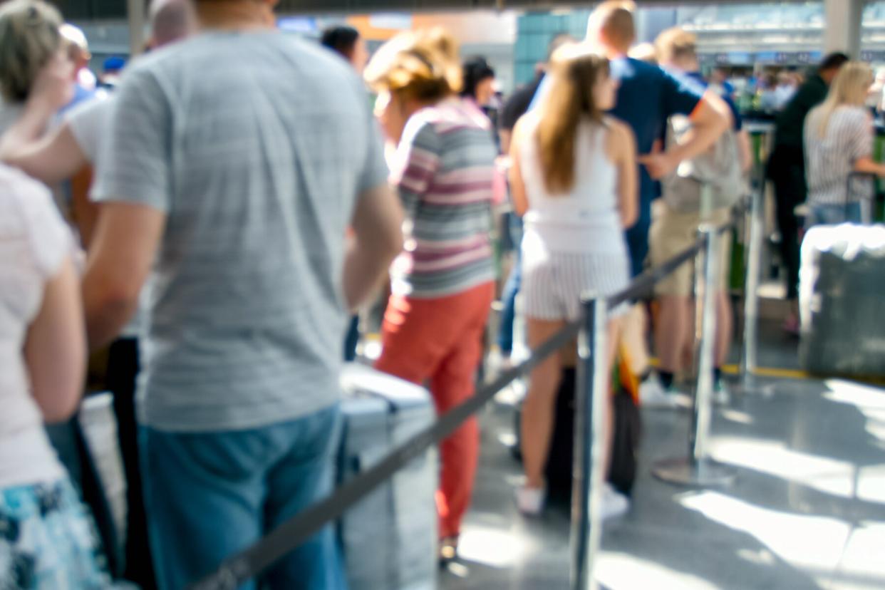 Out of focus image of people waiting in line for check-in on flight at airport terminal