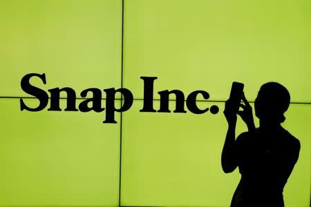 FILE PHOTO - A woman stands in front of the logo of Snap Inc. on the floor of the New York Stock Exchange (NYSE) while waiting for Snap Inc. to post their IPO, in New York City, New York, U.S. on March 2, 2017. REUTERS/Lucas Jackson/File Photo