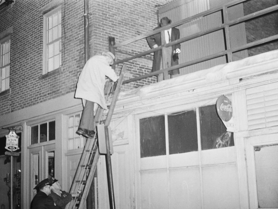 Police check the roof at the back of a building where one of the victims was murdered in 1964.
