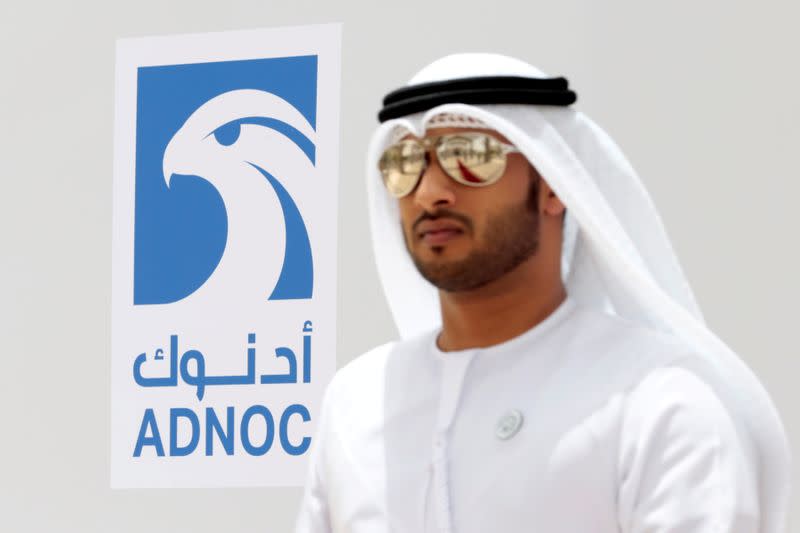 FILE PHOTO: An Emirati man is seen near the logo of ADNOC in Ruwais