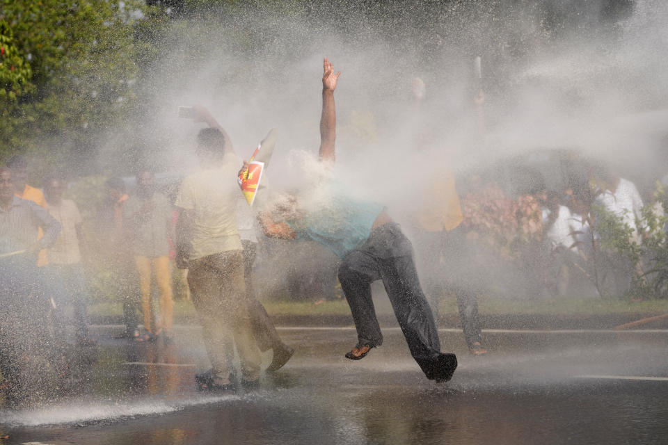 A supporter of Sri Lanka's main opposition loses his balance after being hit by police water cannon during a protest rally against high taxes and increases in electricity and fuel charges, in Colombo, Sri Lanka, Tuesday, Jan. 30, 2024. (AP Photo/Eranga Jayawardena)