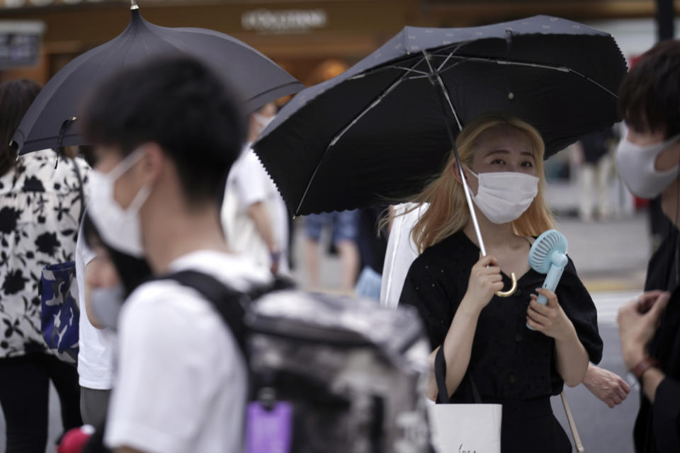 People wearing protective masks to help curb the spread of the coronavirus walk at a Shibuya pedestrian crossing under the scorching sun Thursday, Aug. 13, 2020, in Tokyo. Temperatures rose up over 35 degrees Celsius (95 degrees Fahrenheit) in Tokyo, according to the Japan Meteorological Agency. (AP Photo/Eugene Hoshiko)