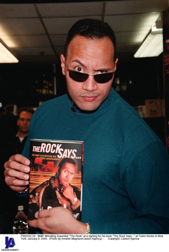 Dwayne "The Rock" Johnson at a book signing event for his book "The Rock Says..." in New York, January 2000, wearing sunglasses and a blue sweater