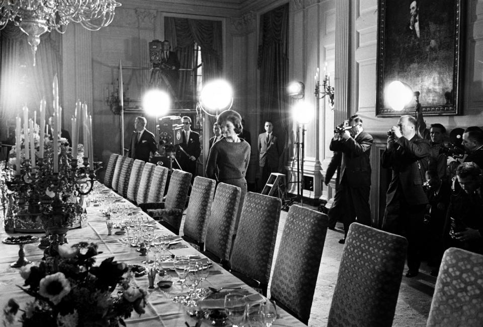 FILE - In this Jan. 15, 1962 file photo, U.S. first lady Jacqueline Kennedy, center, checks the table setting of the White House gold service in the state dining room as she conducts a tour of the newly-restored White House for television cameras in Washington to be aired the month afterwards. More than 80 million Americans tuned in. (AP Photo)