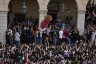 People throw a huge clay jar from a balcony as visitors use their cellphones to film the custom called "botides" on the Ionian Sea island of Corfu, northwestern Greece, on Good Saturday, April 23, 2022. For the first time in three years, Greeks were able to celebrate Easter without the restrictions made necessary by the coronavirus pandemic. (AP Photo/Thanassis Stavrakis)