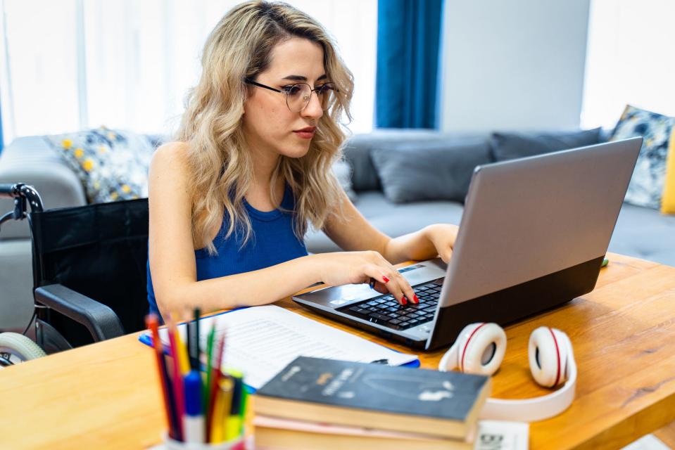 A woman in a wheelchair works on her laptop