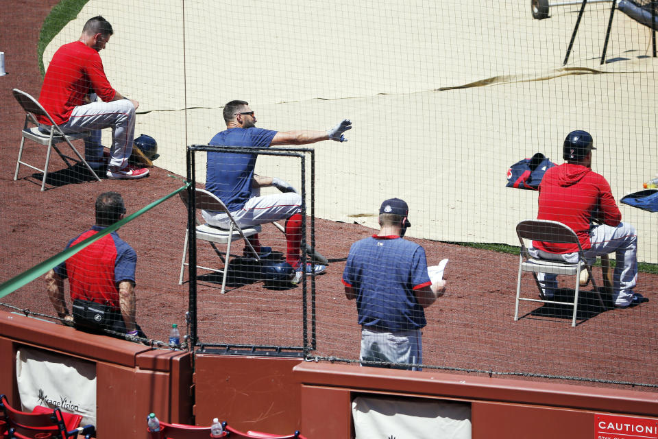 FILE - In this July 5, 2020, file photo, Boston Red Sox players sit apart for social distancing during baseball practice at Fenway Park in Boston. Public health experts have mixed feelings about baseball’s hopes to open its season July 23. There is optimism because of the nature of the sport itself, which produces less on-field risk than basketball, football or hockey. Then again, players and their families face a daunting task staying safe away from the ballpark, especially with teams traveling to and from hard-hit regions including Florida and Texas. (AP Photo/Michael Dwyer)