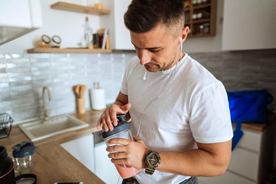 Young man making protein shake before training